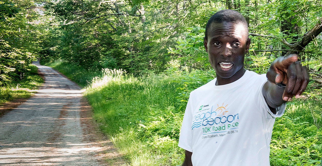 Moninda Marube points to the house on Whitman Spring Trail in Auburn, Maine, while recounting his encounter with a pair of bears that chased him. Marube, a professional runner from Kenya, said he had to outrun the two charging bears while training in the woods Wednesday. (Russ Dillingham / The Lewiston Sun-Journal)