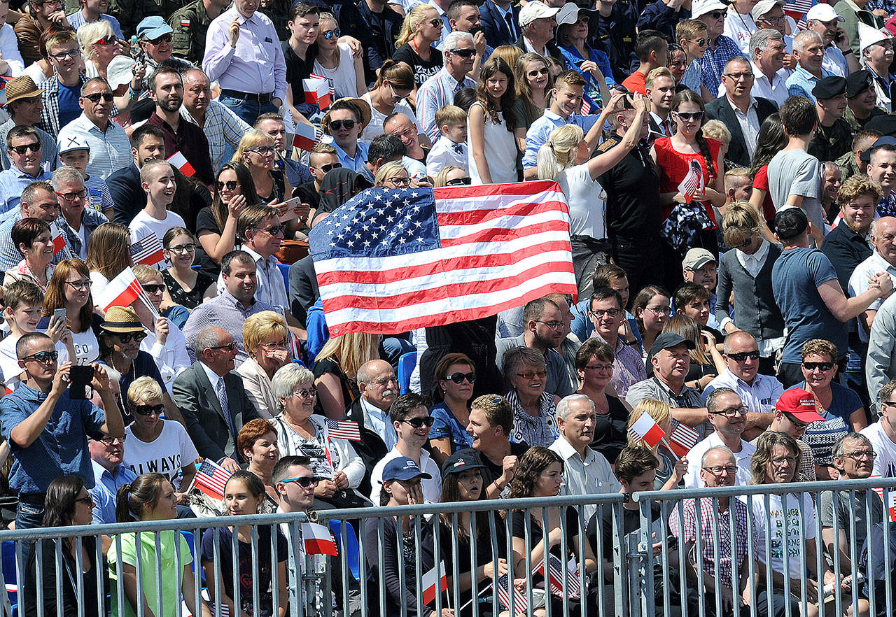 Poles hold a Unites States flag while waiting for U.S. President Donald Trump to deliver a speech in Krasinski Square in Warsaw, Poland, on Thursday. (AP Photo/Alik Keplicz)