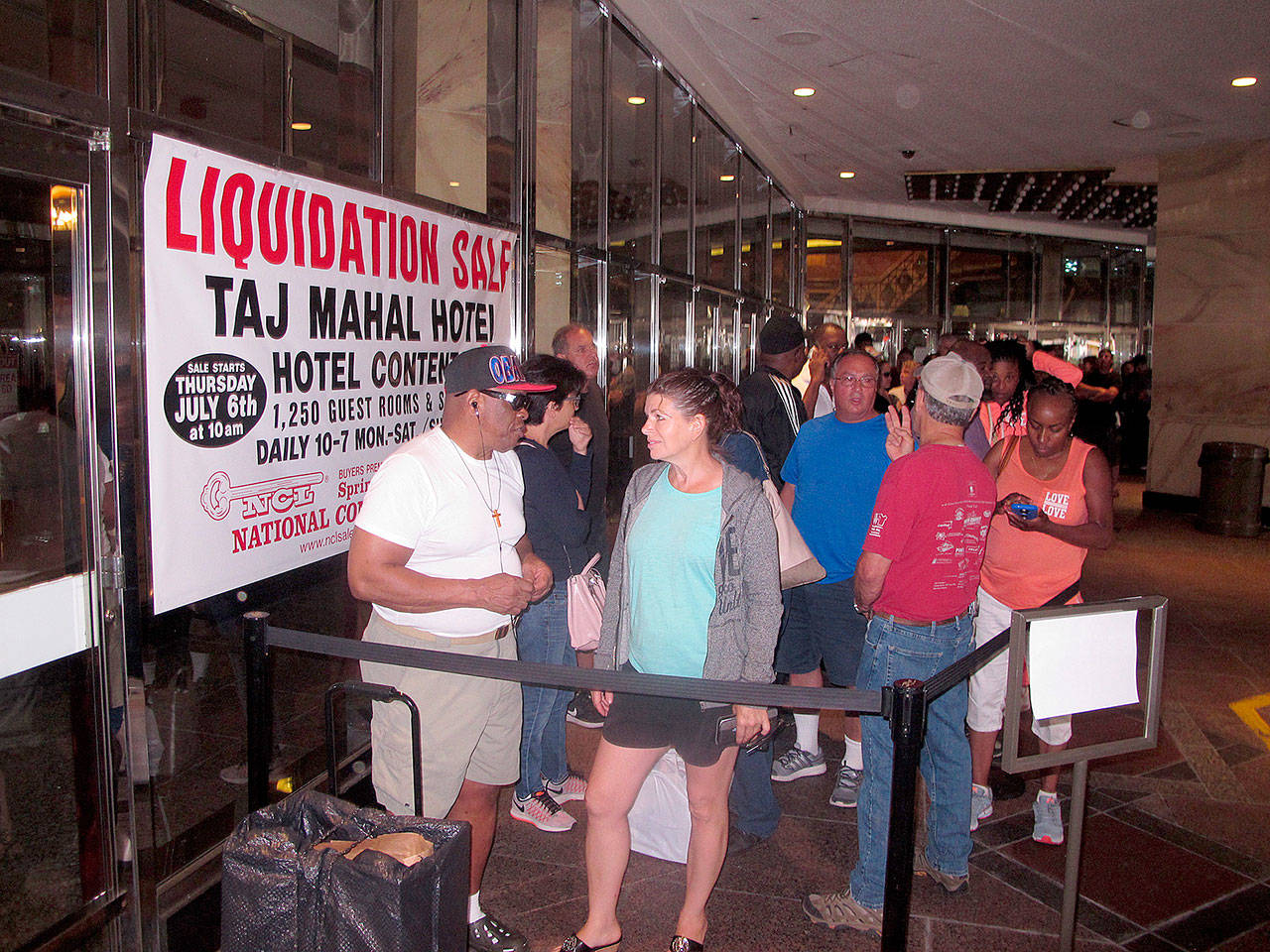 Gerald Winchester, left, chats with Marie Marine, right, as they wait to enter the former Trump Taj Mahal casino in Atlantic City N.J. on Thursday July 6, 2017 for a sale of the casino hotel’s contents. Included in the items for sale were crystal chandeliers from Austria that now-President Donald Trump bought for the casino when he opened it in 1990. The casino shut down last year under different ownership. (AP Photo/Wayne Parry)