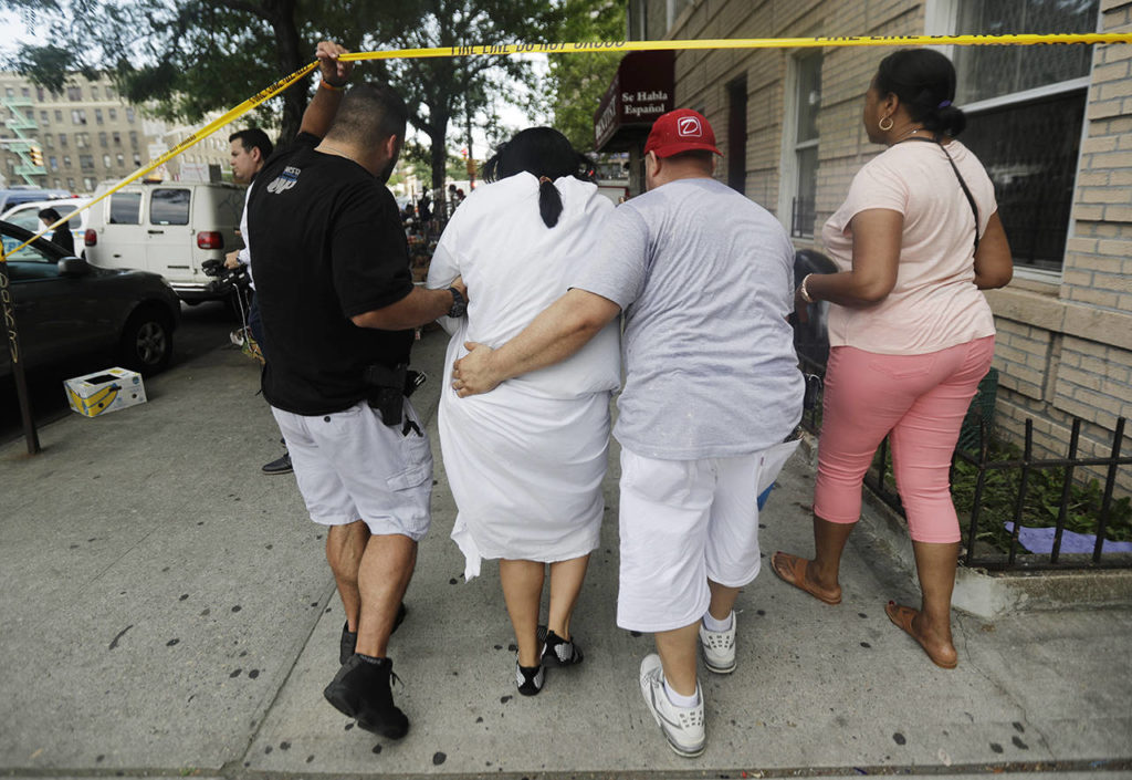 A woman is escorted by officers in plainclothes near the Bronx Lebanon Hospital Center after reports of a shooting Friday in New York. (AP Photo/Julio Cortez)
