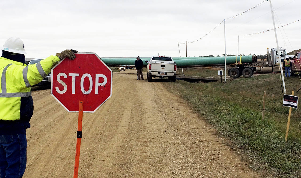 In this 2016 photo, a crew member stops traffic as work resumed on the four-state Dakota Access pipeline near St. Anthony, North Dakota. (AP Photo/Blake Nicholson, File)