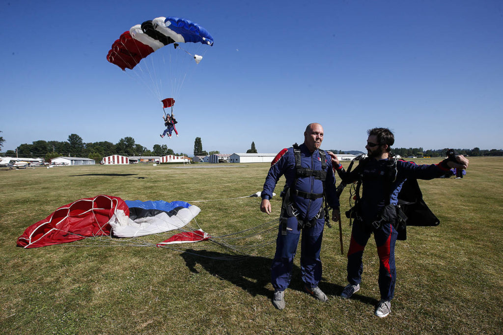 Curtis Zinn (center) lets out a cheer along with his instructor Jordan McElderry (right) after safely landing from a skydive at Skydive Snohomish’s Fill the Sky with Hope event to raise money for Housing Hope on Saturday, July 1. (Ian Terry / The Herald)
