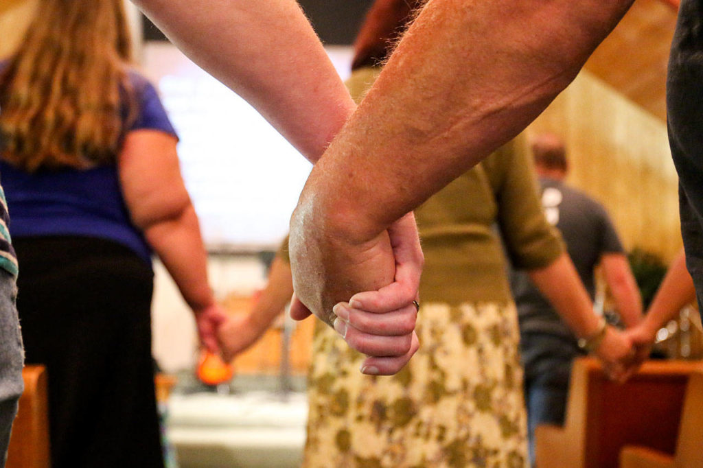 Celebrate Recovery participants hold hands during a meeting at Snohomish Church of the Nazarene in Snohomish on June 18. (Kevin Clark / The Herald)

