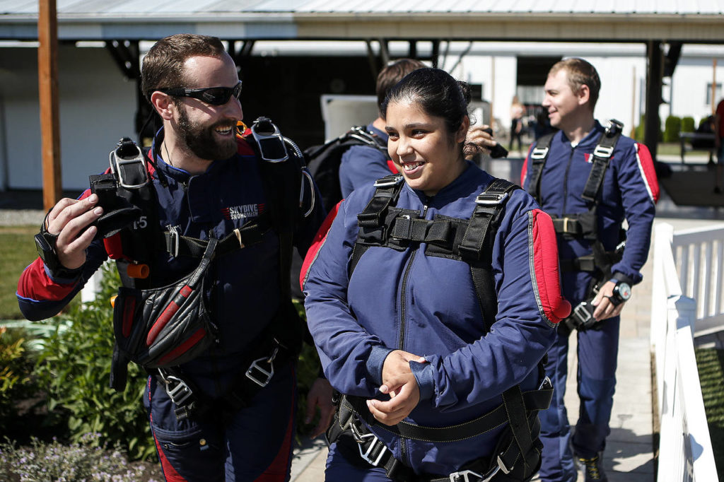 Yessica Ramos (right) is led by her instructor out to a waiting plane before skydiving at Skydive Snohomish’s Fill the Sky with Hope event on Saturday, July 1. (Ian Terry / The Herald)
