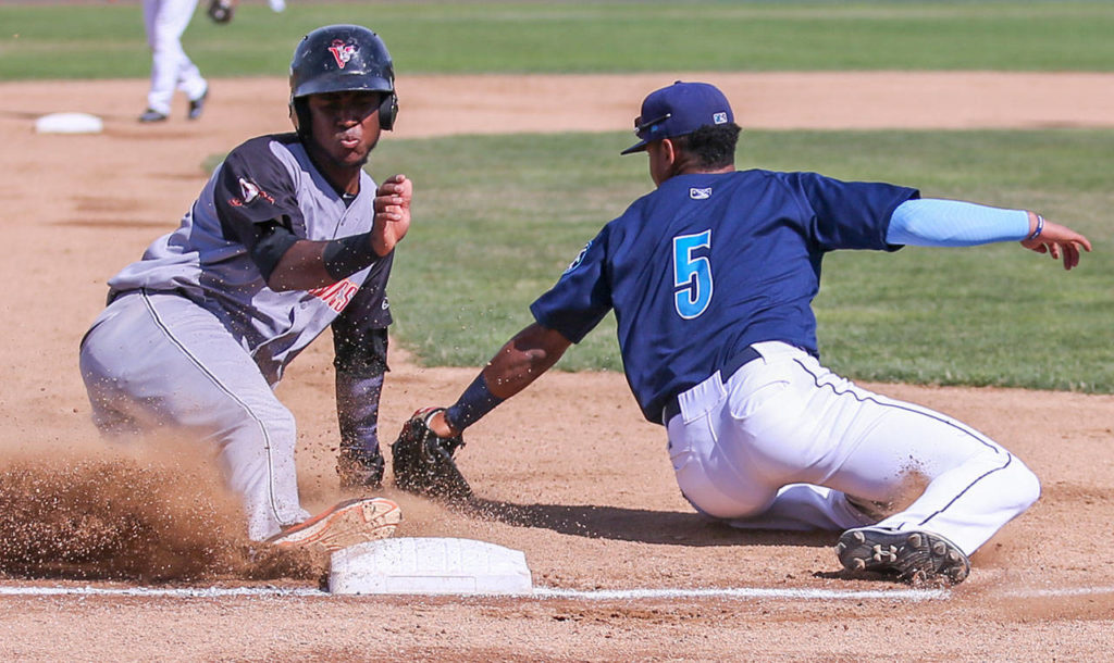 Salem-Keizer’s Manuel Geraldo slides safely third base with Everett’s Chris Torres attempting a tag into Sunday afternoon at Everett Memorial Stadium in Everett on July 9, 2017. Salem-Keizer won 7-6. (Kevin Clark / The Herald)
