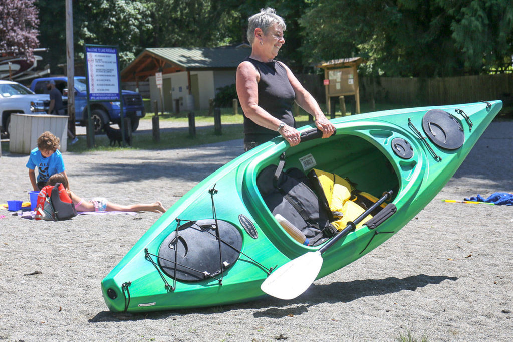 Karon Carroll hauls her new kayak to Lake Roesiger Sunday afternoon at Lake Resiger Park in Snohomish on July 2, 2017. (Kevin Clark / The Herald)
