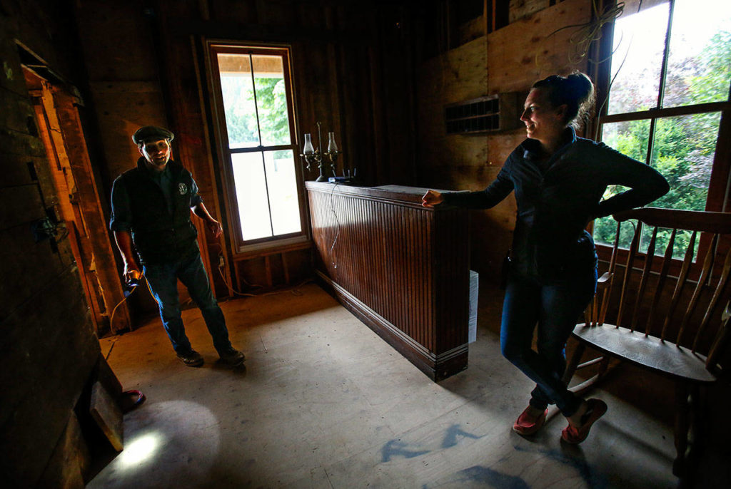 Blair Corson enters a small room on the southwest corner of the hotel where his wife, Kathy, waits. He carries a flashlight, which he’ll use to illuminate something special he found near the bottom of an old staircase in the next room. It is the signature of the original owner of the building, Clarence Bush, who moved to Index in 1899 with his wife, Ella. (Dan Bates / The Herald)
