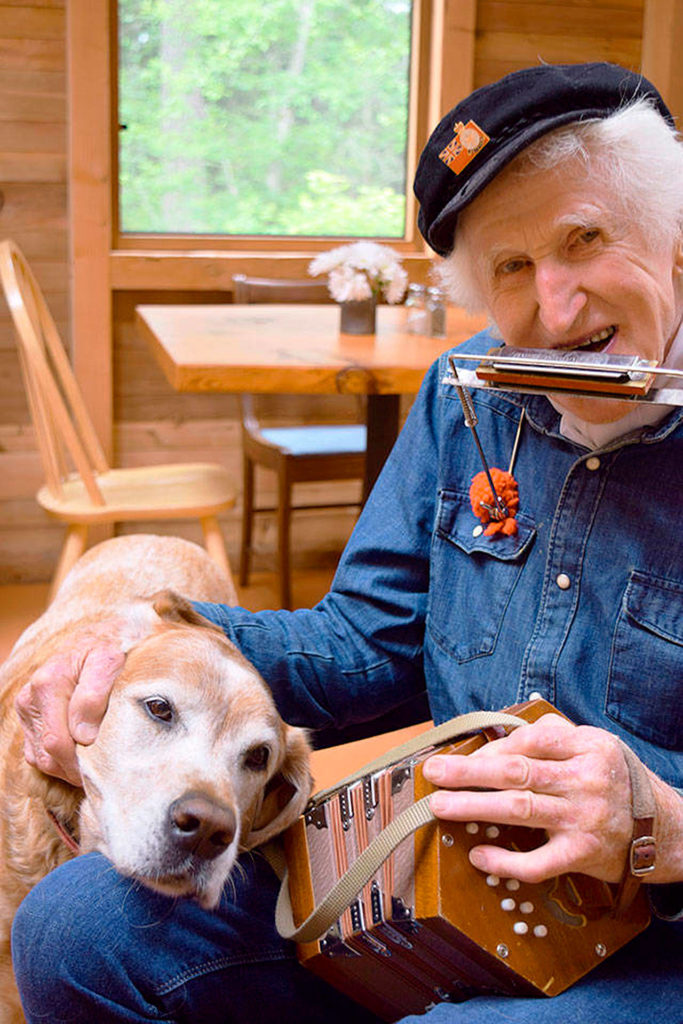Peter Lawlor and his dog, Claude, are Saturday morning regulars at Cafe in the Woods near Langley. For customers, he plays and sings songs of the sea from his worldwide travels. The native New Zealander, 95, has lived in Clinton the past dozen years. “I’m proud of my age,” he says. “I think I’ve had a good go.” (Patricia Guthrie/Whidbey News-Times)
