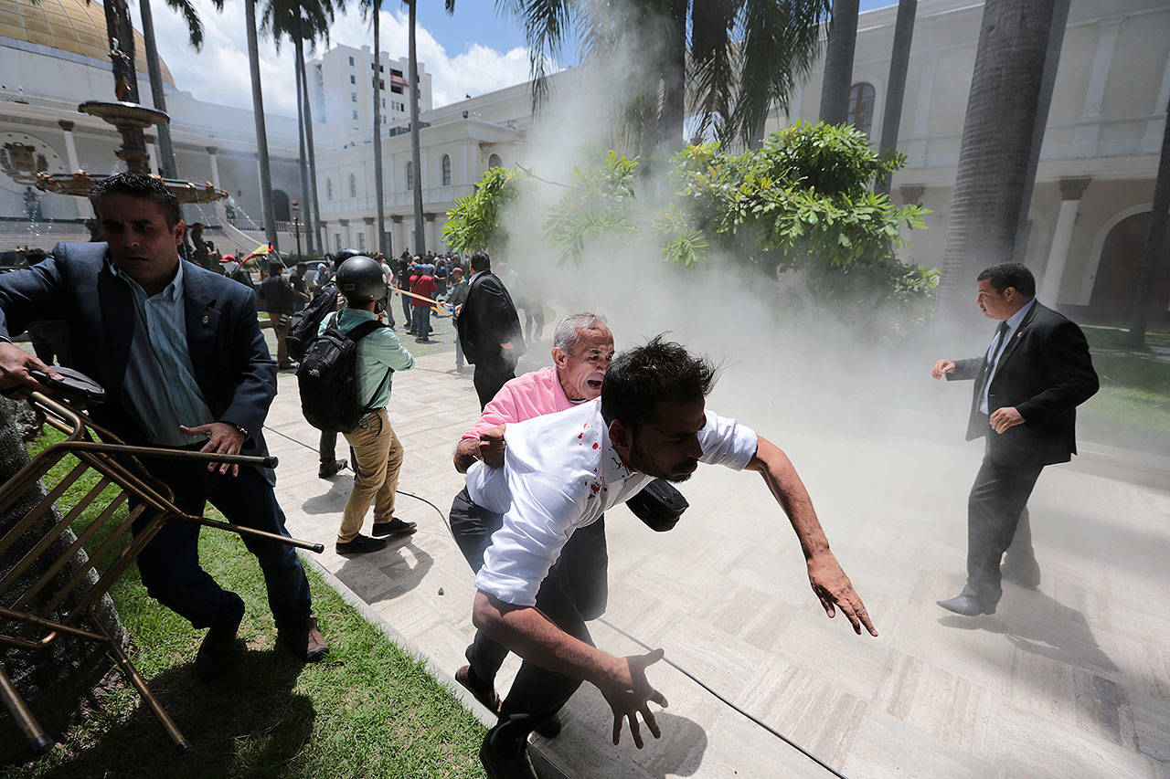 Opposition lawmaker Armando Armas, center front, and National Assembly workers run from pro-government militia members attacking opposition lawmakers and assembly employees during a special session coinciding with Venezuela’s independence day, in Caracas, Venezuela, on Wednesday. Pictured right is opposition congressman Simon Calzadilla. (AP Photos/Fernando Llano)