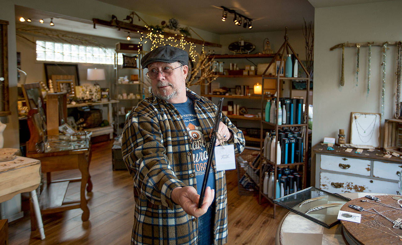 Bill Butcher, of Marysville, shows off an art piece to his wife as they shop at Beach Glass. (Andy Bronson / The Herald)