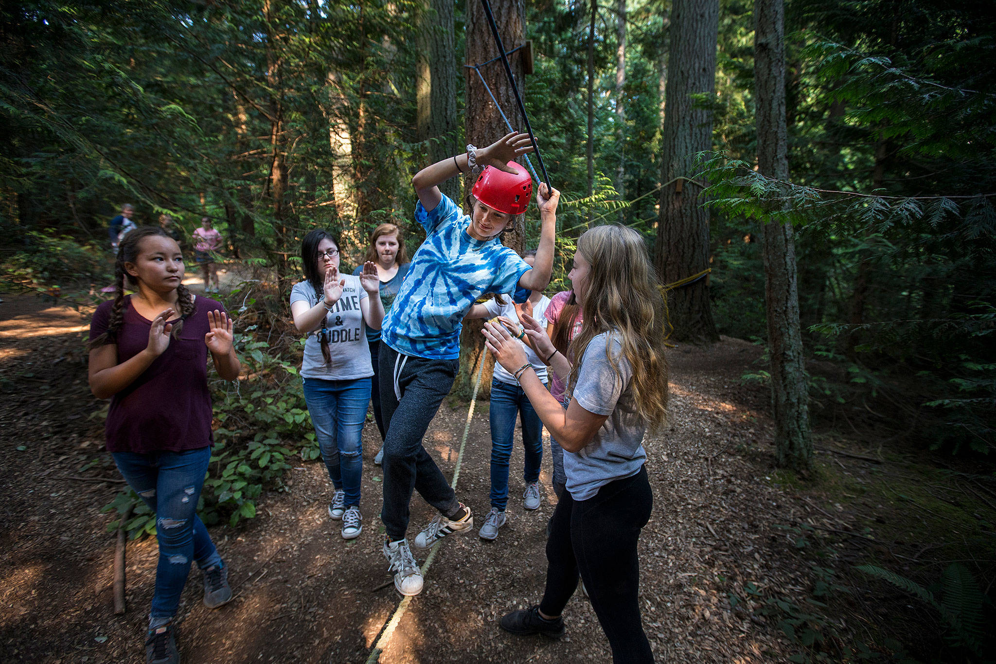 With fellow campers ready to catch her if she falls, Dane Palm, 14, of Seattle, hangs on during the low ropes course at Camp Killoqua on Monday in Stanwood. (Andy Bronson / The Herald)