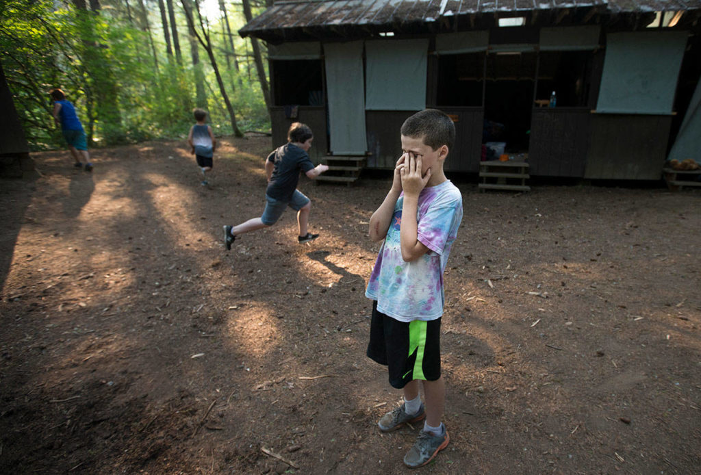 Eli Zerba, 11, of Seattle, counts off as fellow campers hide during a game called “Thicket” at Camp Killoqua on Monday in Stanwood. The game is similar to “Hide-and-Seek,” but the counter never moves and players must be somewhat visible to the counter. (Andy Bronson / The Herald)
