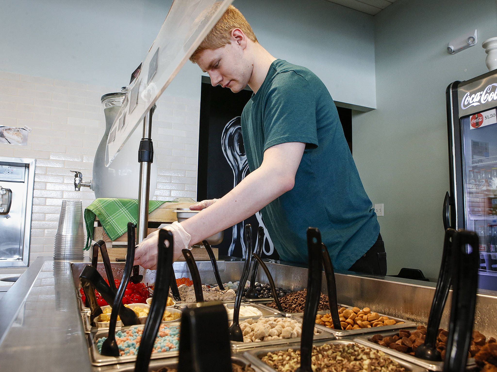 Ryan Outsen, 21, refills containers of frozen yogurt toppings at The Creamery Co. in Marysville on July 26. Outsen works at the store two days a week as part of the city’s Inclusive Workplace Partners Program, which began last year. (Ian Terry / The Herald)