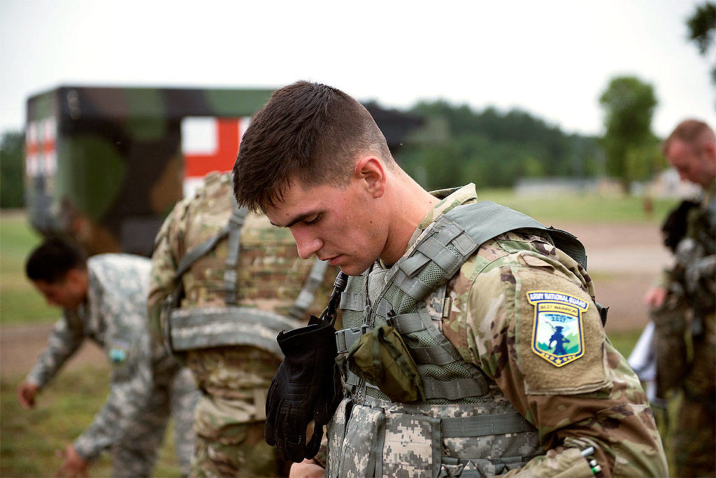 Sgt. Grant Reimers, a heavy vehicle driver with 1859th Light-Medium Transport Company, Nevada National Guard, puts on his gear after completing an Army Physical Fitness Test and before they begin an unknown distance run event on July 18 at Camp Ripley, Minn., for the 2017 Army National Guard Best Warrior Competition. The distance run event consisted of a two-mile run with various tasks, including carrying crawling under barbed wire and three to five second rushes, and finishing by dragging a 100-pound Sked 100 meters. (Minnesota National Guard photo by Sgt. Sebastian Nemec)
