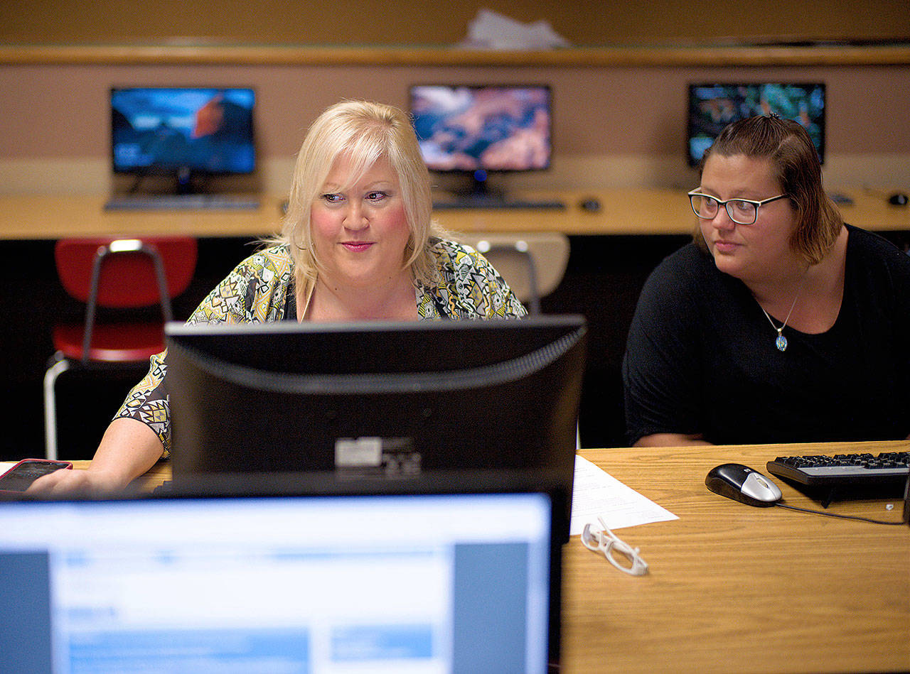 Cheryl Bast, accompanied by her daughter Liz Pierson, works on an application for a position with Omaha Public Schools during a job fair in Omaha, Nebraska, in July. (AP Photo/Nati Harnik)