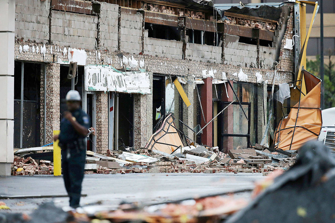 A man stands near a damaged building after a storm moved through the area in Tulsa, Oklahoma, on Sunday. A possible tornado struck near midtown Tulsa and causing power outages and roof damage to businesses. (Tom Gilbert/Tulsa World via AP)