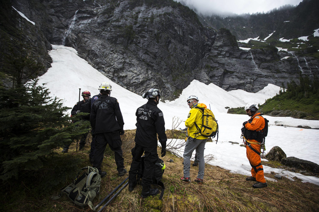 Snohomish County Search and Rescue members, including Oyvind Henningsen (center right), wait to be lifted out of their location via helicopter during training at the Big Four Ice Caves on June 10. (Ian Terry / The Herald)
