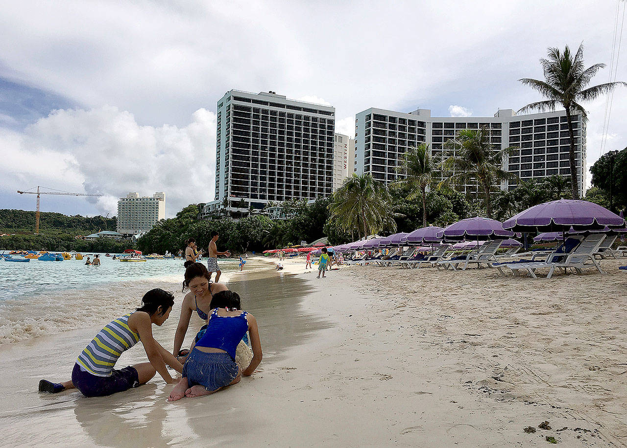 A family plays in the sand in Tumon, Guam, on Thursday. The small U.S. territory of Guam has become a focal point after North Korea’s army threatened to use ballistic missiles to create an “enveloping fire” around the island. (AP Photo/Tassanee Vejpongsa)