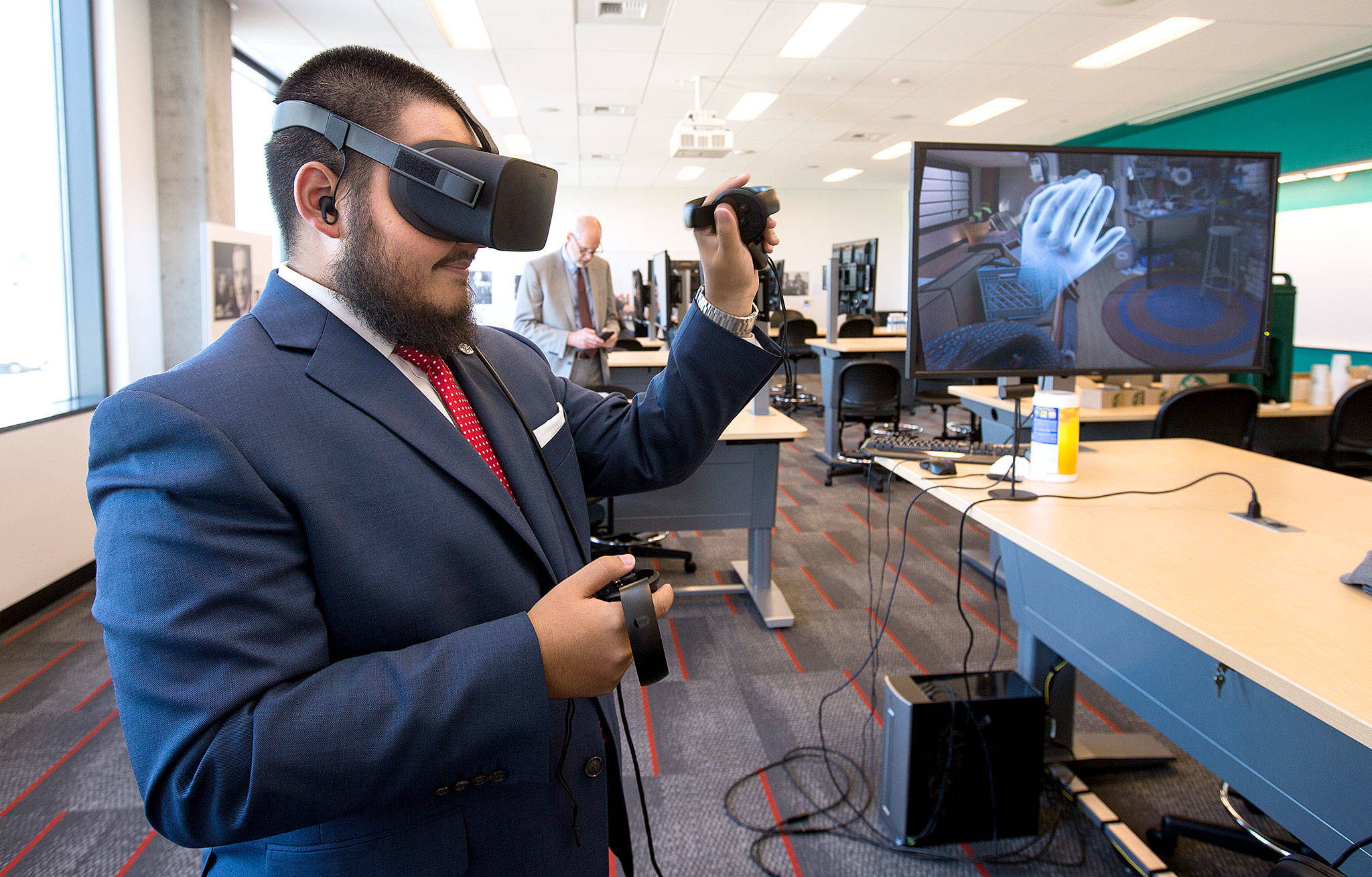 Sharief Yusuf waves as he uses a 3-D simulator during an open house at the Washington State University Everett building on Tuesday. The 3-D units will allow students with a fear of public speaking to use it to simulate talking in front of an audience when taking communication classes. (Andy Bronson / The Herald)