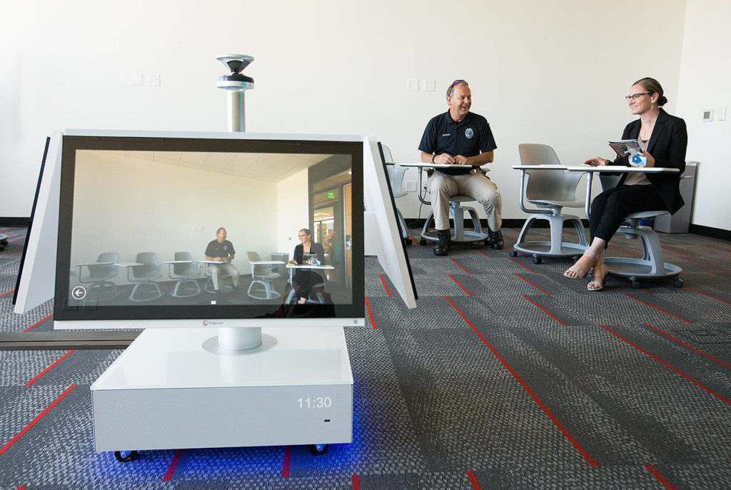 WSU assistant police chief Steve Hansen and Molly Shotzko, director of marketing, sit in a classroom equipped with a 360-degreemonitor during an open house and ribbon-cutting ceremony at the Washington State University Everett building on Tuesday. (Andy Bronson / The Herald)
