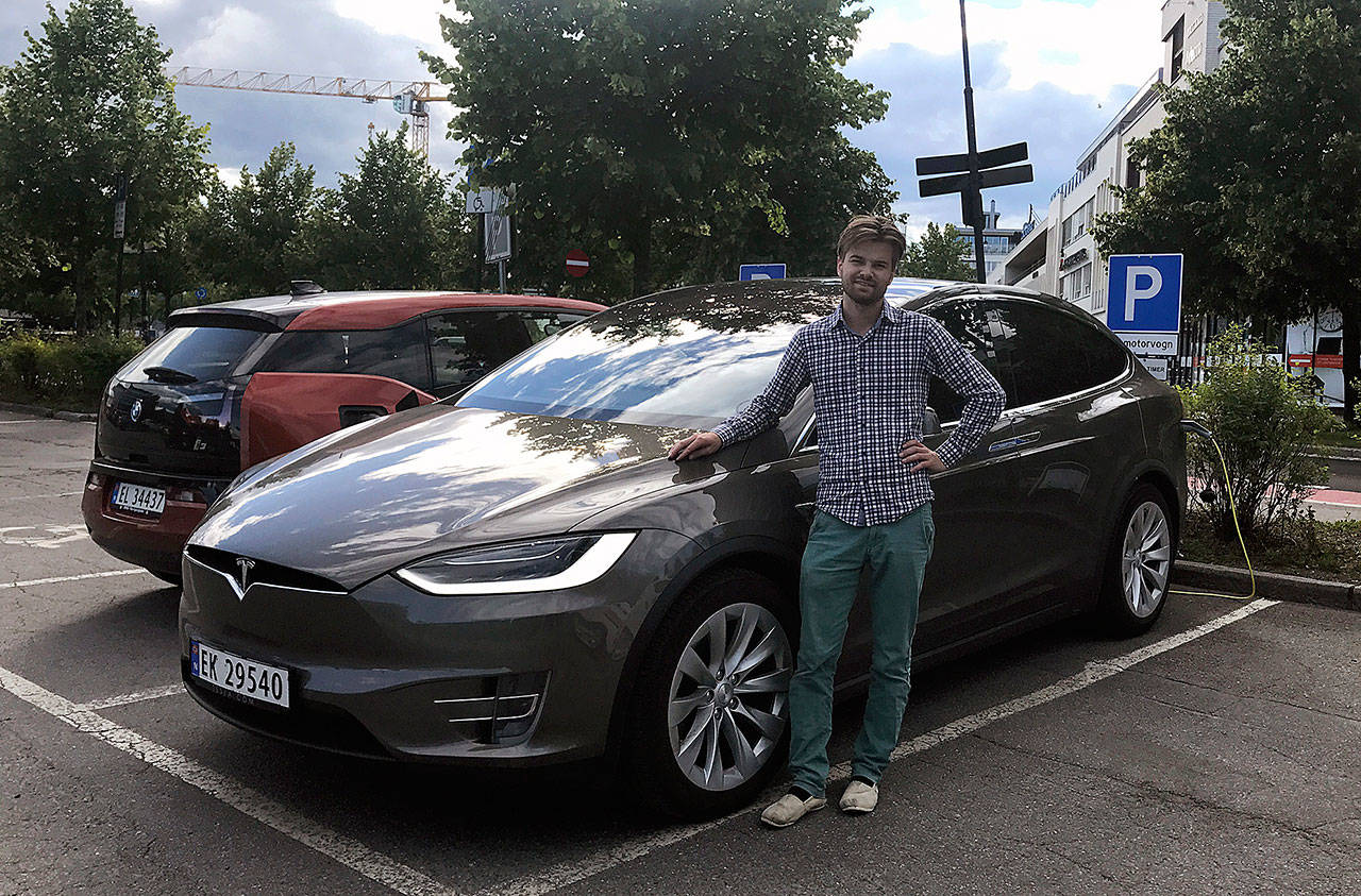 Nils Henningstad poses next to his Tesla Model X in July while charging the electric car at a public charging station in Lillestrom, Norway. (Lene Marie Brynildsen)
