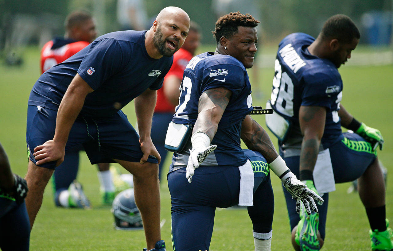 Seahawks defensive coordinator Kris Richard (left) talks with rookie running back Chris Carson during an Aug. 7 training camp session in Renton. (AP Photo/Ted S. Warren)