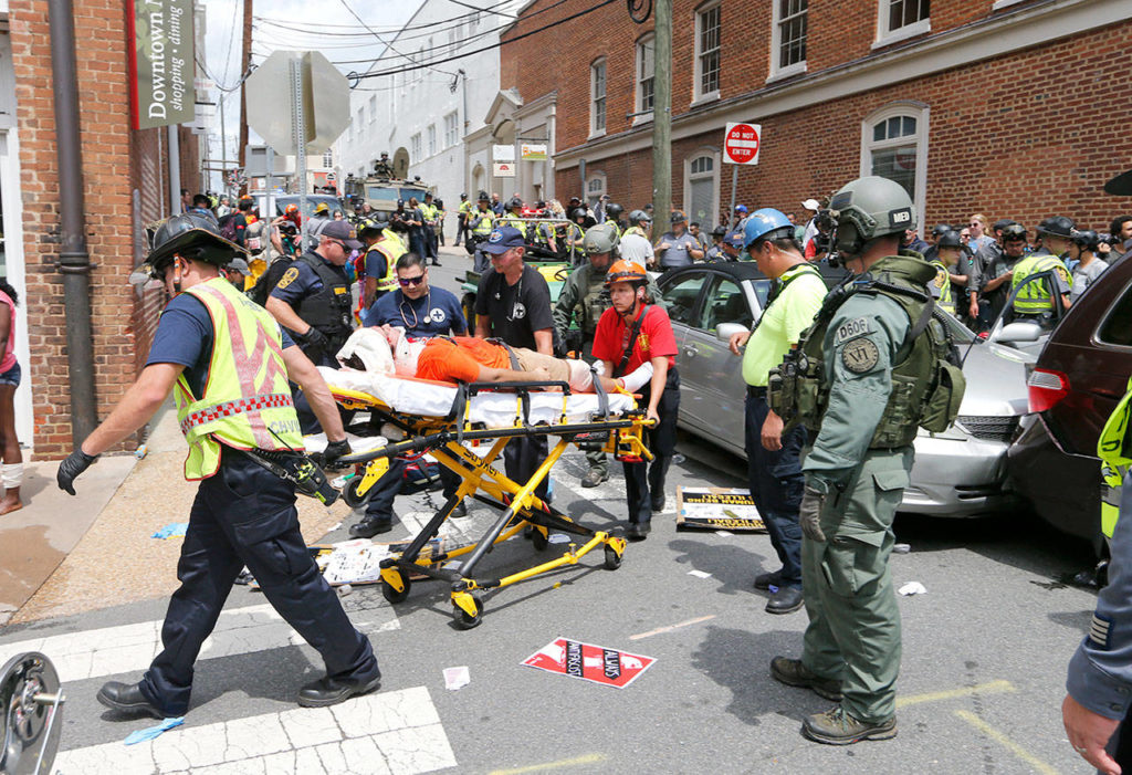 Rescue personnel help injured people after a car ran into a large group of protesters after an white nationalist rally in Charlottesville, Virginia, on Saturday. (AP Photo/Steve Helber)
