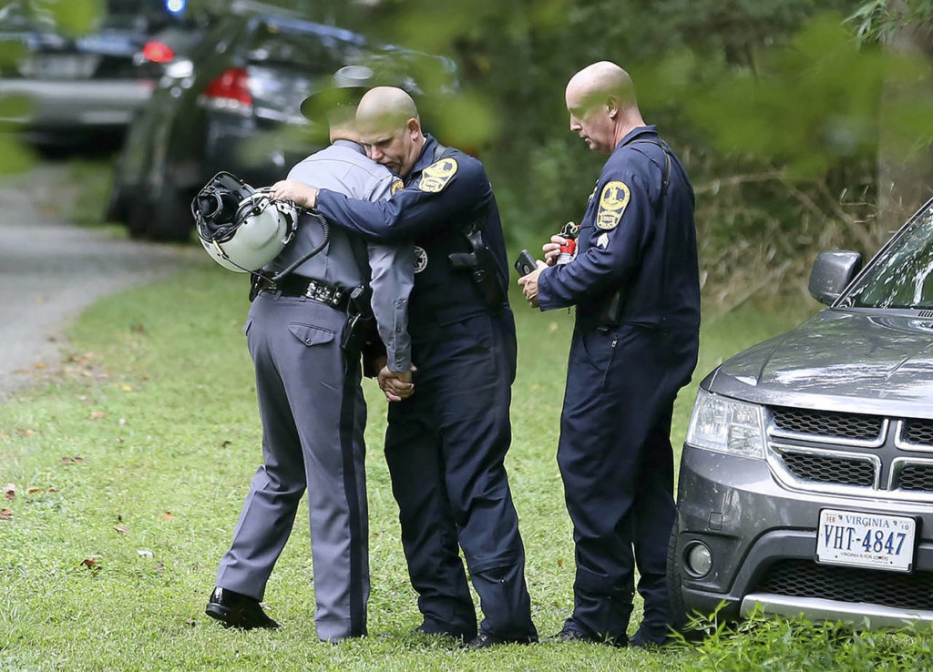 Authorities embrace while working near the scene of a deadly helicopter crash near Charlottesville, Virginia, on Saturday. (Shelby Lum/Richmond Times-Dispatch via AP)
