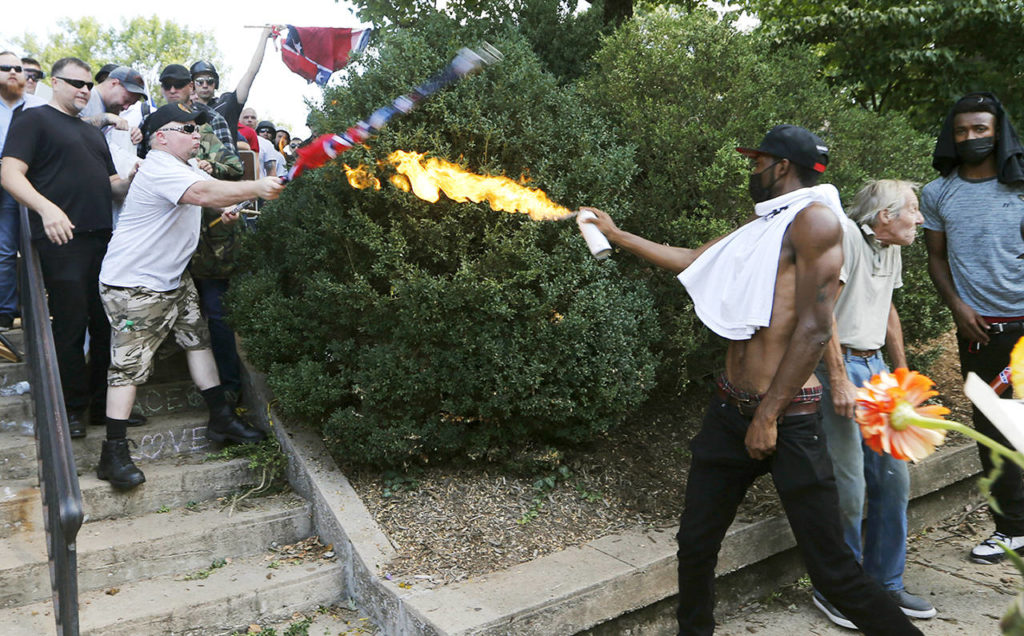 A counter demonstrator uses a lighted spray can against a white nationalist demonstrator at the entrance to Lee Park in Charlottesville, Virginia, on Saturday. (AP Photo/Steve Helber)
