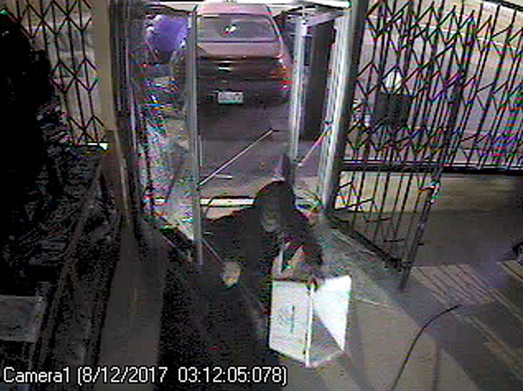 An image from surveillance video at Everett pawn shop Pawn Father’s, which was robbed Saturday when a car backed through the glass door and a metal gate and three people wearing hoods entered. They stole dozens of guns. (Bureau of Alcohol, Tobacco, Firearms Explosives)
