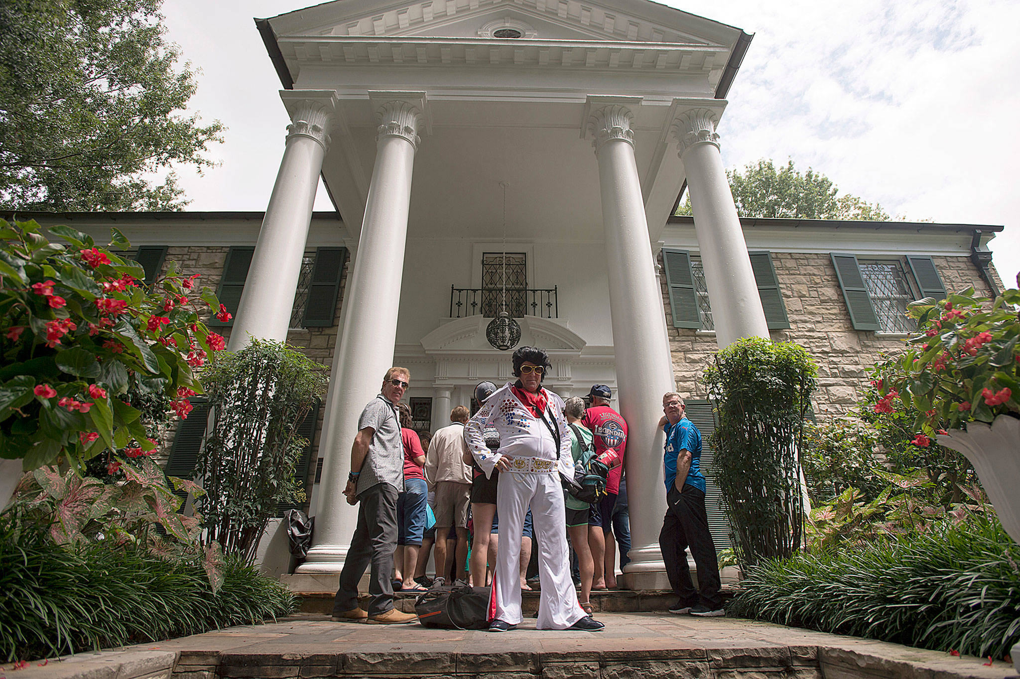 Bryan Glencross of Glasgow, Scotland, strikes a pose in his Elvis-inspired outfit while waiting to begin a tour of Graceland on Tuesday in Memphis, Tennessee. (AP Photo/Brandon Dill)