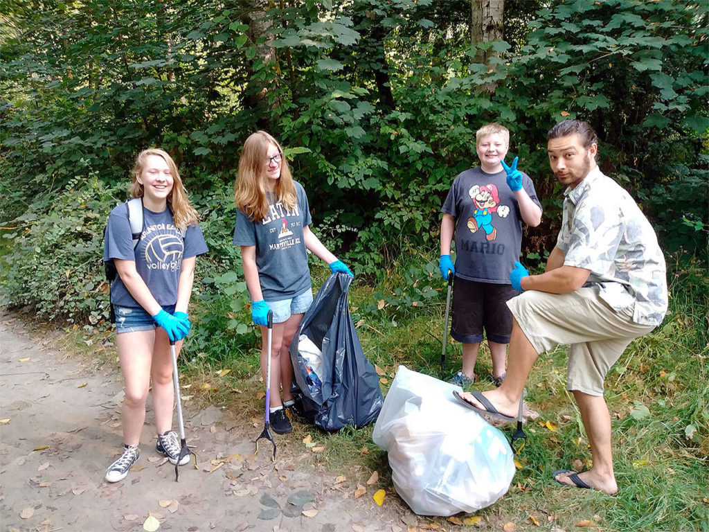 Christina Zuber (from left), Emily Wilson, Joe Wilson and youth pastor Antonio Baiamonte from the Arlington Christ the King Community Church youth group recently cleaned up over two dozen large trash bags’ worth of garbage at Twin Rivers Park. (Contributed photo)
