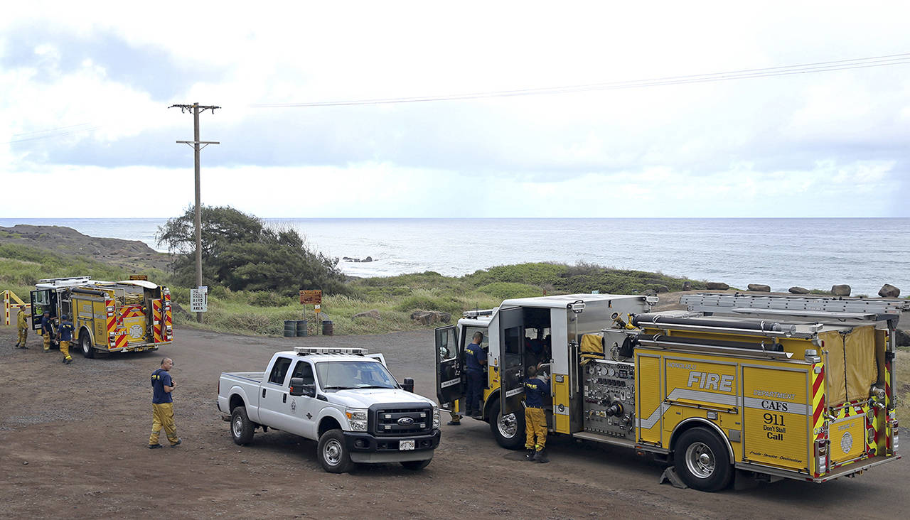 Honolulu Fire Department members gather at the entrance of Kaena Point on Wednesdayin Waialua, Hawaii. An Army helicopter with five on board crashed several miles off Oahu’s North Shore late Tuesday. (AP Photo/Marco Garcia)