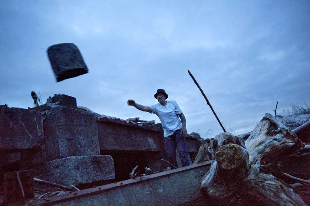 Scott Stevens collects wood from the shore to light a fire in a homeless encampment, where he lives along the river, in Aberdeen on June 14. (AP Photo/David Goldman)
