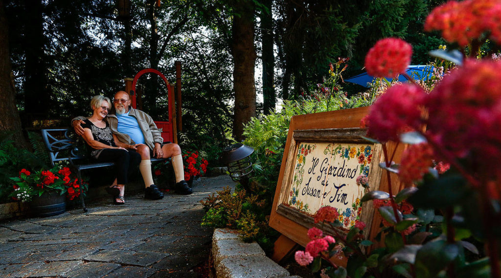 Jim and Susan enjoy a bench along a curved pathway that connects a number of resting spots as it winds around the garden. (Dan Bates / The Herald)
