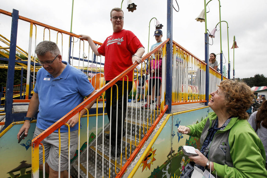 Joel Lloyd (center), 21, of Snohomish, is greeted by his mother, Bonnie (right), as he walks down the steps from a rollercoaster ride with his father, Mark, at the Evergreen State Fair in Monroe on Wednesday. (Ian Terry / The Herald)
