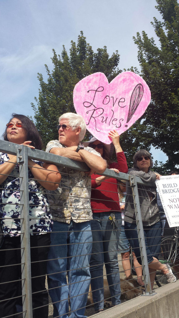 A “Rally Against Hate” participant holds up a sign that says “Love Rules!” during the gathering Sunday at the Snohomish County campus plaza in Everett. (Diana Hefley / The Herald)
