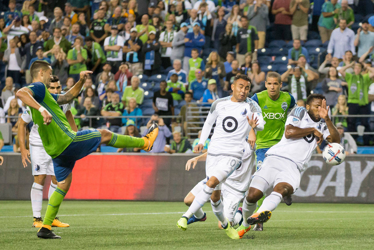 Minnesota United defender Jermaine Taylor (right) commits a handball in the box to award the Sounders a penalty kick in stoppage time. Seattle’s Clint Dempsey (left) converted the penalty kick, giving the Sounders a 2-1 win Sunday in Seattle. (Bettina Hansen / The Seattle Times via AP)