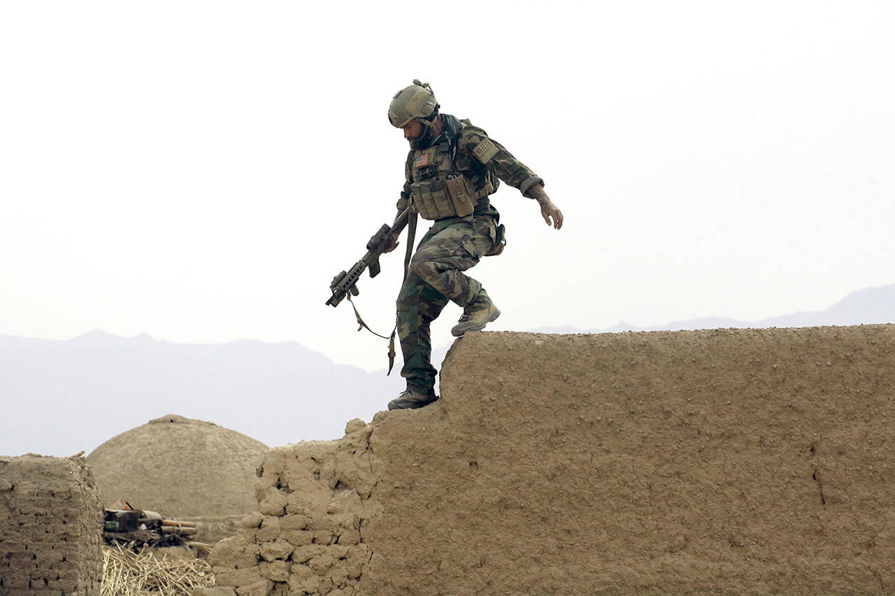 In this 2009 photo, a U.S. special operations forces servicemember climbs down from a compound wall after investigating suspicious activity, during a joint patrol with Afghan National Army soldiers in Shewan, a former Taliban Stronghold, in Afghanistan’s Farah province. (AP Photo/Maya Alleruzzo)