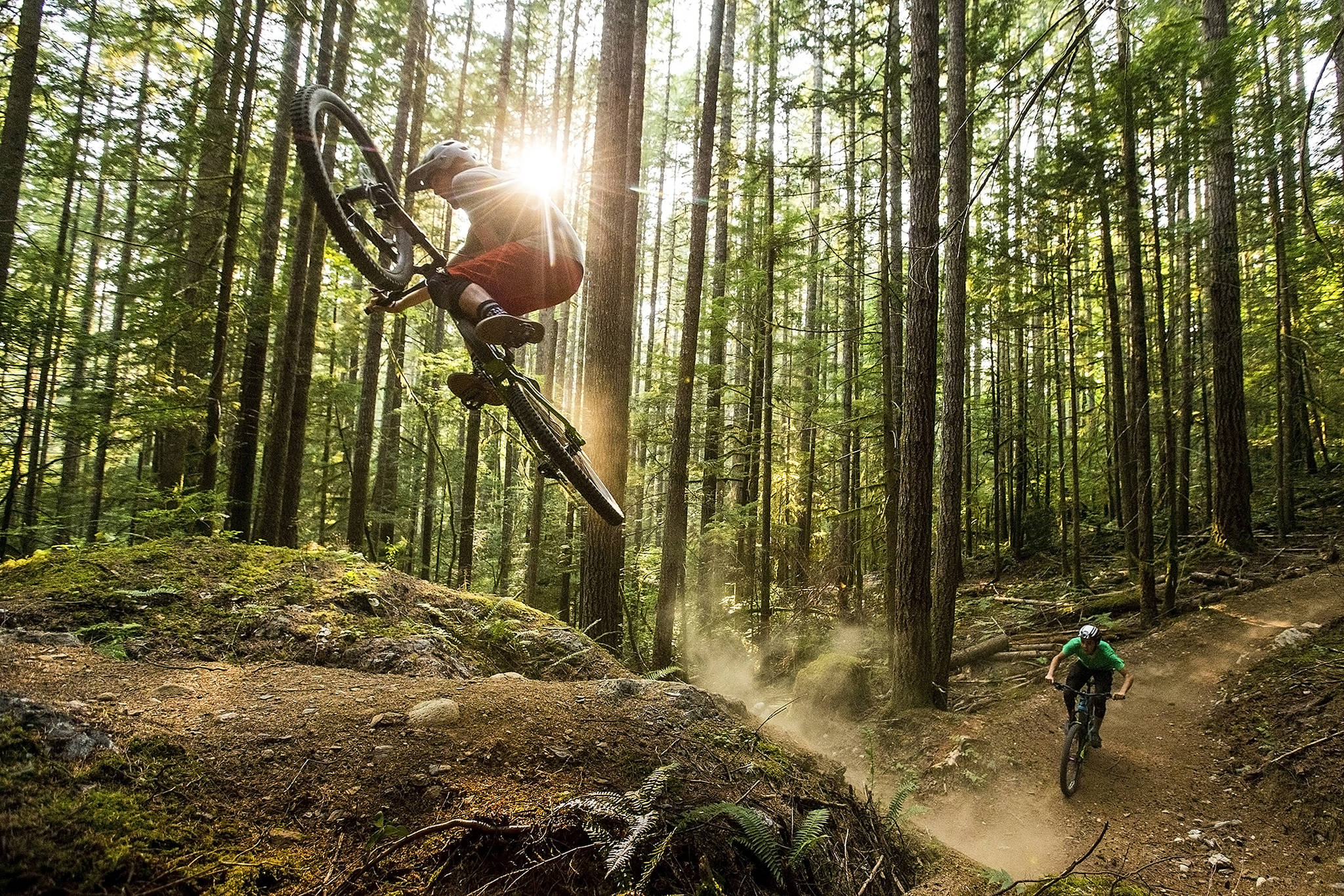 Skye Schillhammer (left) catches air off a rocky lip as Oliver Parish exits a corner on Darrington’s new mountain bike trail system, located at the base of North Mountain. Schillhammer grew up in Darrington and now resides in Bellingham where he works for Transition Bikes, a mountain bike manufacturer. (Ian Terry / The Herald)