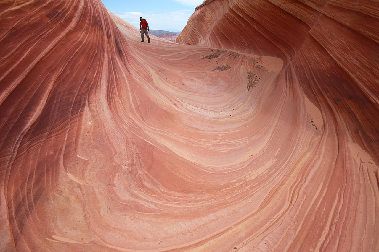 In this 2013 photo, a hiker walks on a rock formation known as The Wave in the Vermilion Cliffs National Monument in Arizona. (AP Photo/Brian Witte, File)