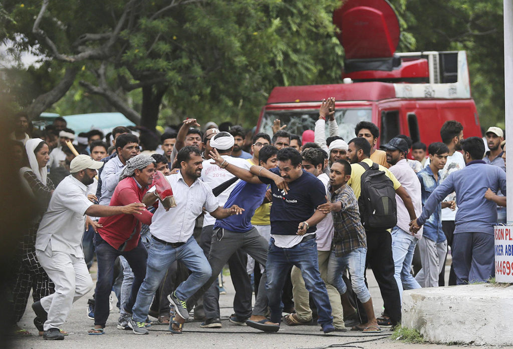 Supporters of the Dera Sacha Sauda sect attack a member of the media, foreground wearing a blue dark T-shirt, in Panchkula, India, on Friday. (AP Photo/Altaf Qadri)
