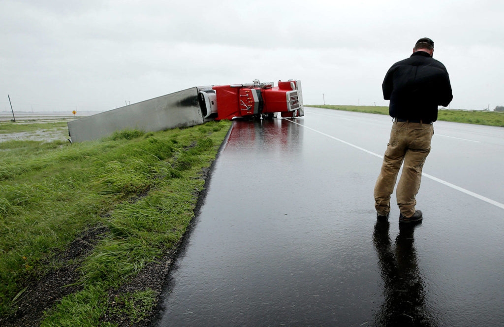 A passing motorist stops to look at a flipped truck in the aftermath of Hurricane Harvey on Saturday, north of Victoria, Texas. (AP Photo/Charlie Riedel)
