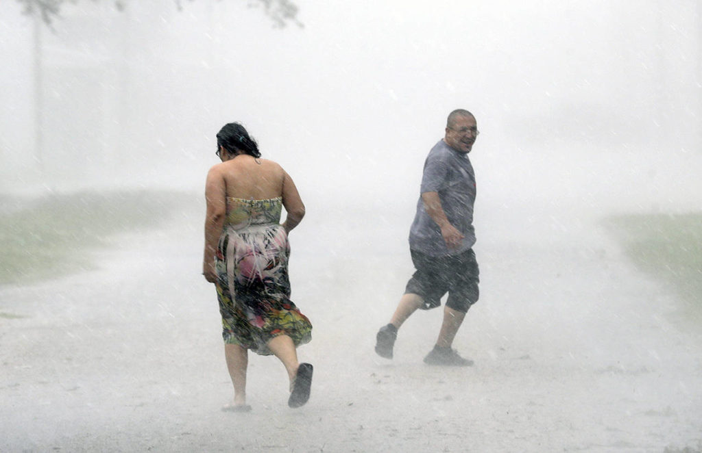 Antonio Barron (right) looks back to his girlfriend, Melissa Rocha, as they run through the street during a band of heavy rain from Hurricane Harvey on Saturday in Palacios, Texas. (AP Photo/David J. Phillip)
