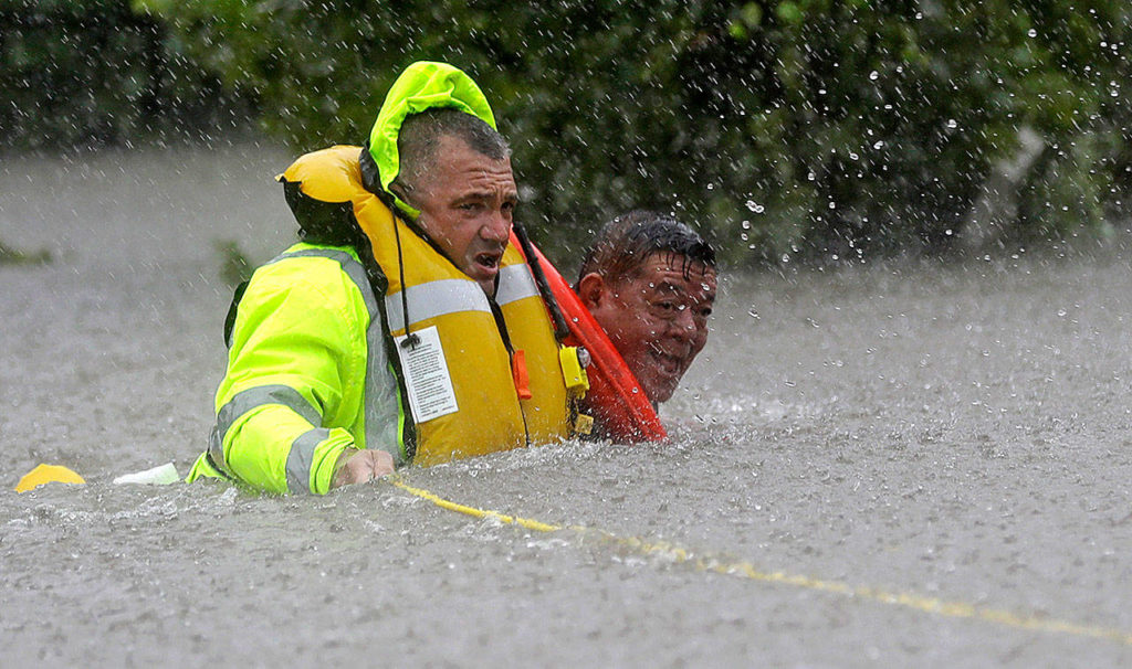 Wilford Martinez (right) is rescued from his flooded car by Harris County Sheriff’s Department Richard Wagner along Interstate 610 in floodwaters from Tropical Storm Harvey on Sunday in Houston, Texas. (David J. Phillip / Associated Press)
