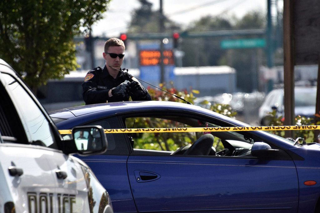 A police officer examines the scene of a shooting on Evergreen Way. (Caleb Hutton / The Herald)
