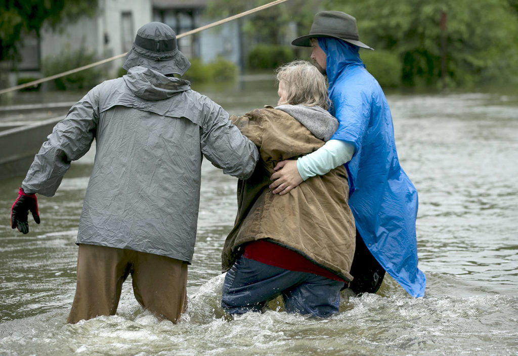 Volunteers help a woman after she was rescued by boat from her home in Beaumont, Texas, in the aftermath of Harvey on Wednesday. (Jay Janner/Austin American-Statesman via AP)
