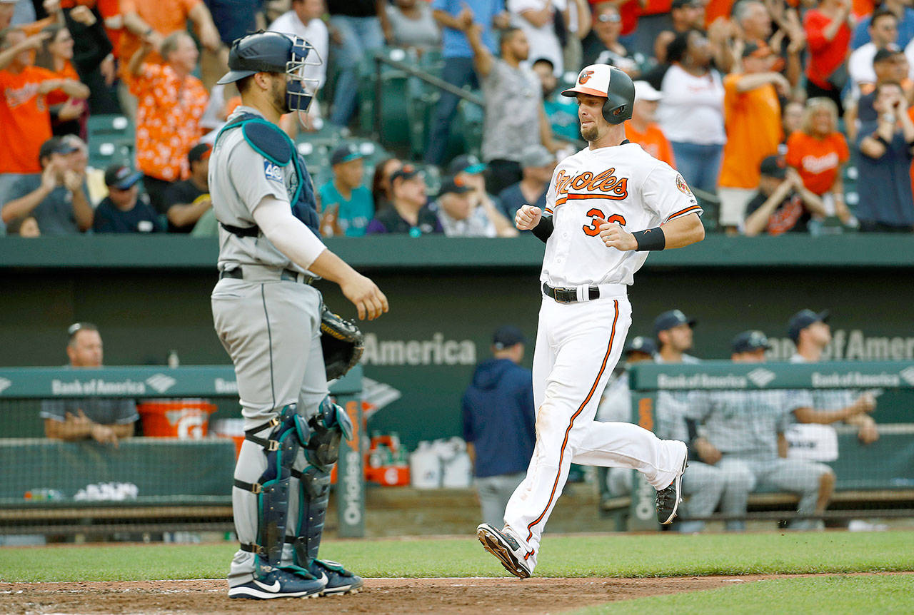 Baltimore’s Caleb Joseph (right) runs past Seattle’s Mike Zunino with the eventual game-winning run after a Jonathan Schoop’s single in the eighth inning of the Orioles’ 8-7 win over the Mariners on Wednesday in Baltimore. (AP Photo/Patrick Semansky)