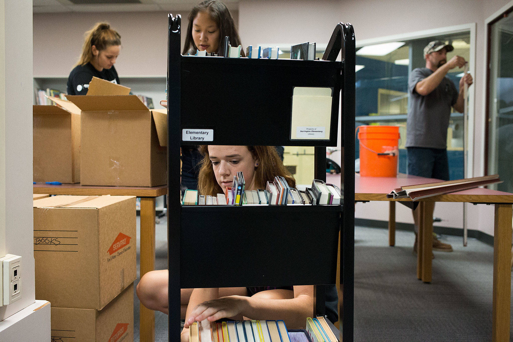 Alexis Korr (center) organizes boxes of books in the library at Darrington Elementary School with friends Mikah Dewberry and Kayla Misanes on Thursday. Class preparations were curtailed for weeks after vandals broke in and tore apart classrooms, broke windows, and sprayed fire extinguishers everywhere. (Andy Bronson / The Herald)