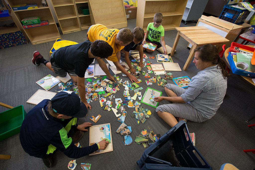Volunteers match pieces of their puzzles in the preschool room at Darrington Elementary School on Thursday. (Andy Bronson / The Herald)

